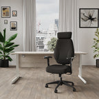 Black office chair and desk in a home office setting with a big window and plants in the background