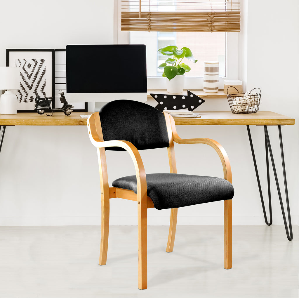 Wooden chair with black cushion in front of a wooden desk with a computer setup.