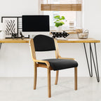 Black chair with wooden frame in front of a desk with office items.