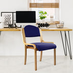 Blue chair with wooden frame in front of a desk with office decor.