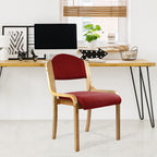 Red chair with wooden frame in front of a desk with office decor.