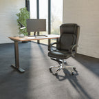 Modern office desk with a leather chair and computer setup in a bright room.