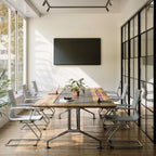 Modern conference room with a large table, chairs, and a mounted screen.