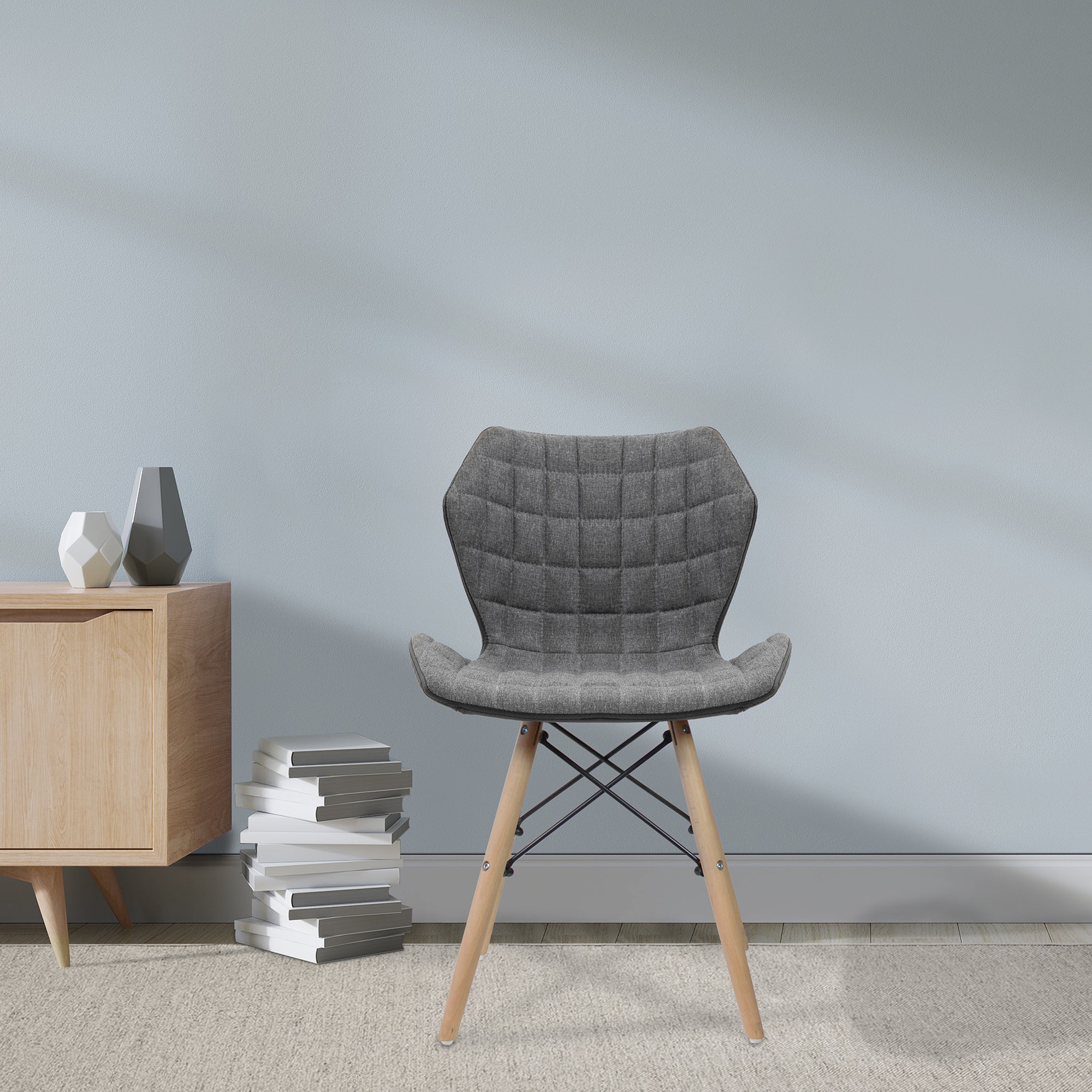 Grey upholstered chair with wooden legs in a room with a light grey wall and wooden side table.