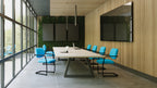 Modern conference room with a large table and blue chairs near large windows.