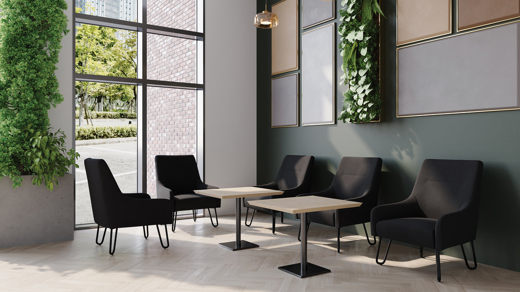 Modern waiting room with black chairs and tables near large windows.