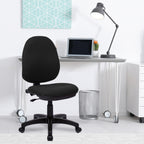 Black office chair in front of a white desk with a laptop and lamp.