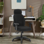 Black office chair in front of a white desk with a lamp and books in a room with a brown wall and plants.