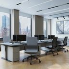 Modern office space with desks, chairs, and large windows overlooking a cityscape.