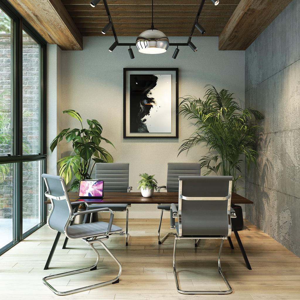 Modern office space with grey chairs, a wooden desk, and decorative plants.