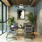 Modern office space with grey chairs, a wooden desk, and decorative plants.