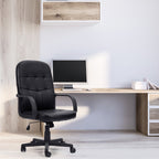 Black office chair in front of a wooden desk with a computer setup.