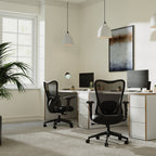 Modern office setup with two black chairs, a desk, and computer monitors.