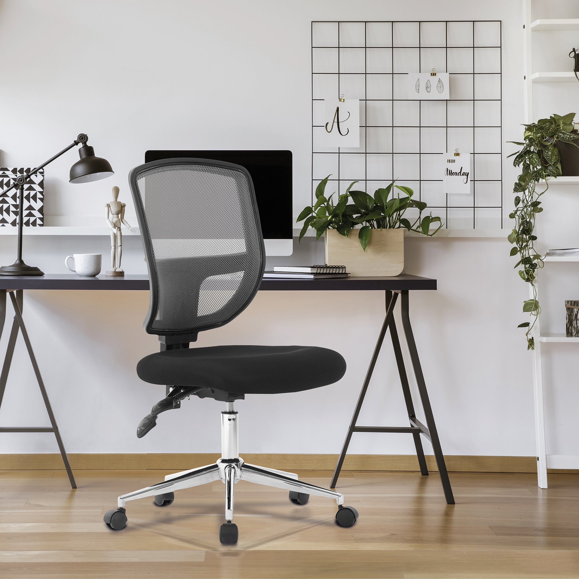 Black office chair in front of a desk with a computer and decor items.
