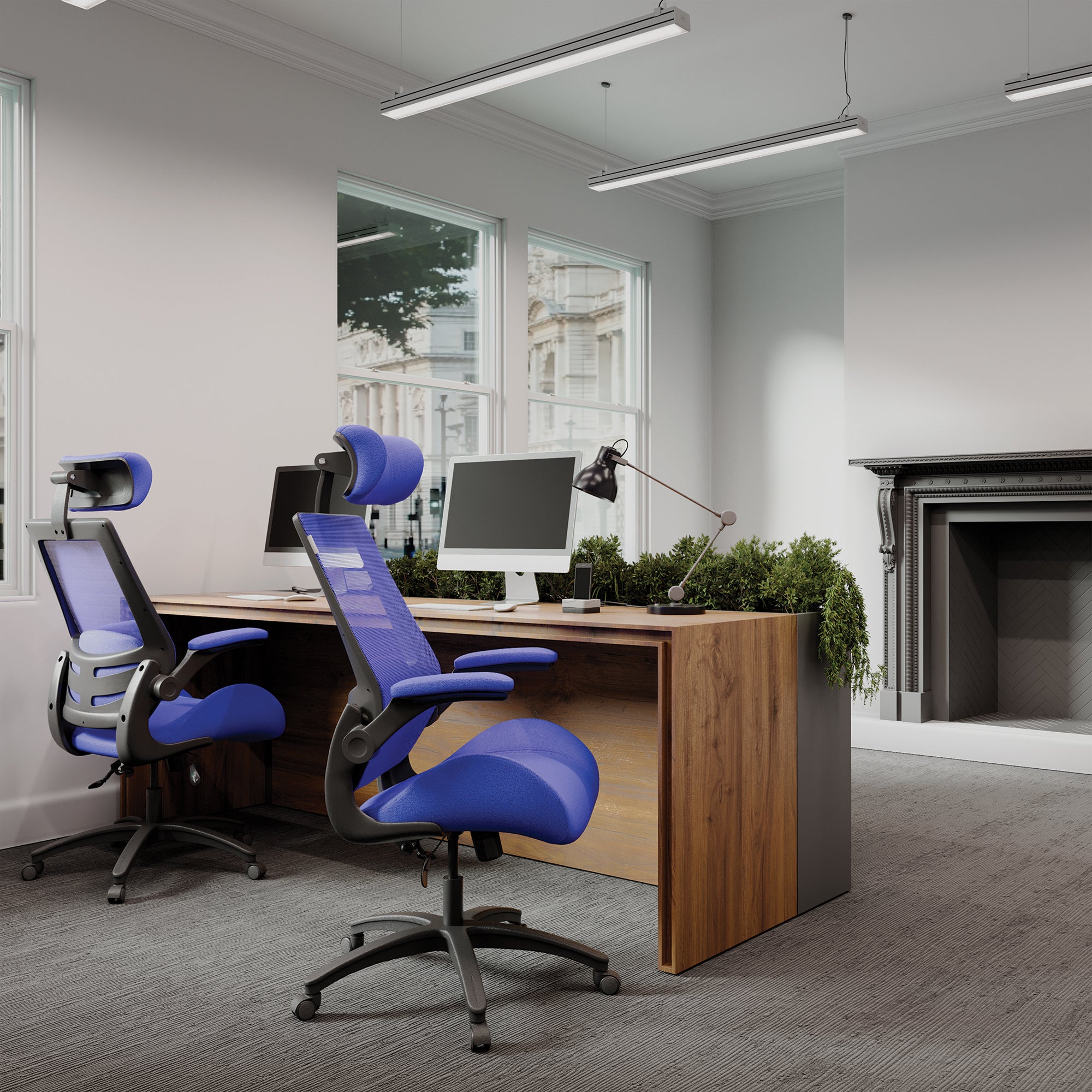 Modern office setup with wooden desk, computer monitors, and blue ergonomic chairs.