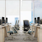 Modern office setup with ergonomic chairs and computer monitors in a bright room.