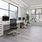 Modern office with desks, chairs, and large windows.