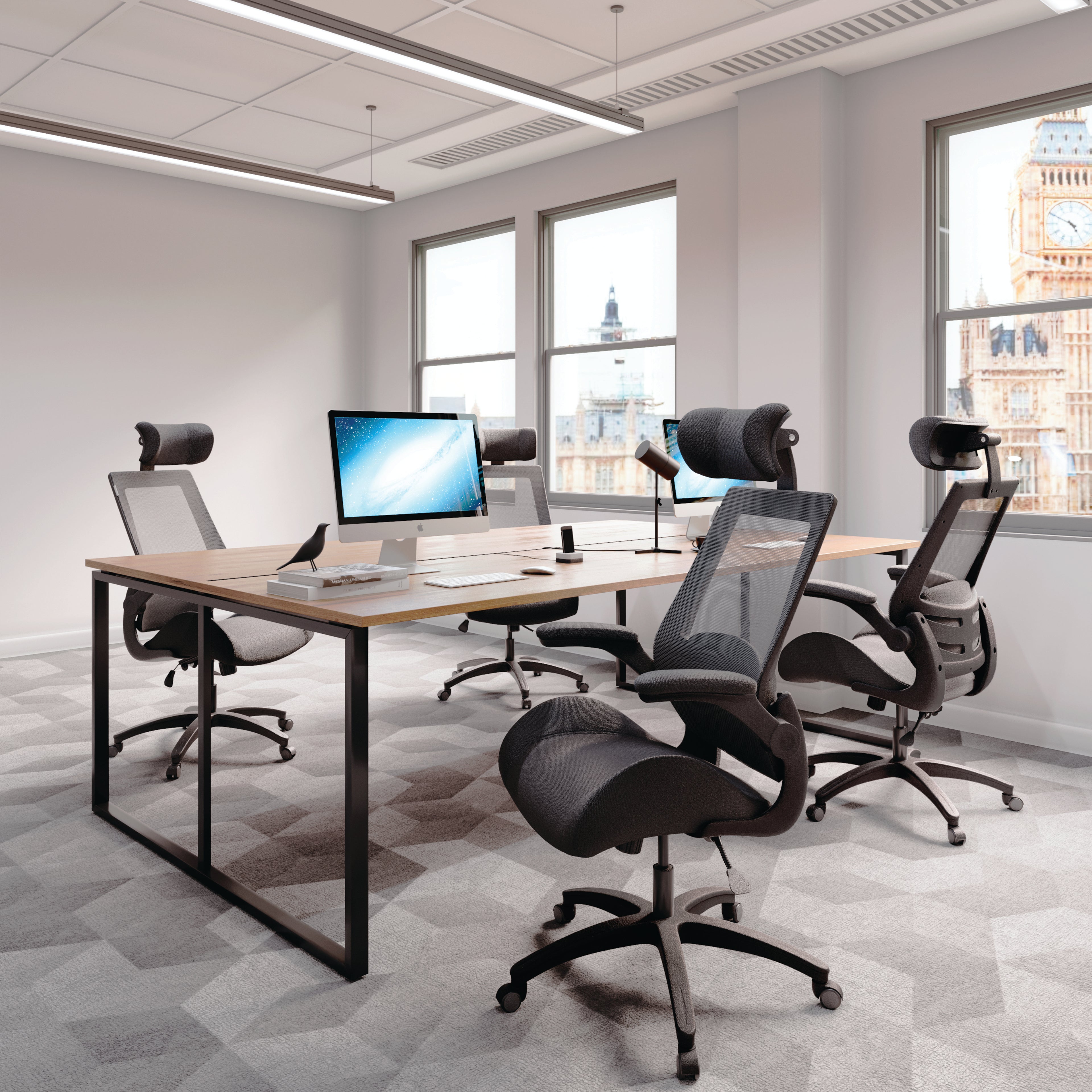 Modern office setup with desks, chairs, and computer monitors in a bright room.