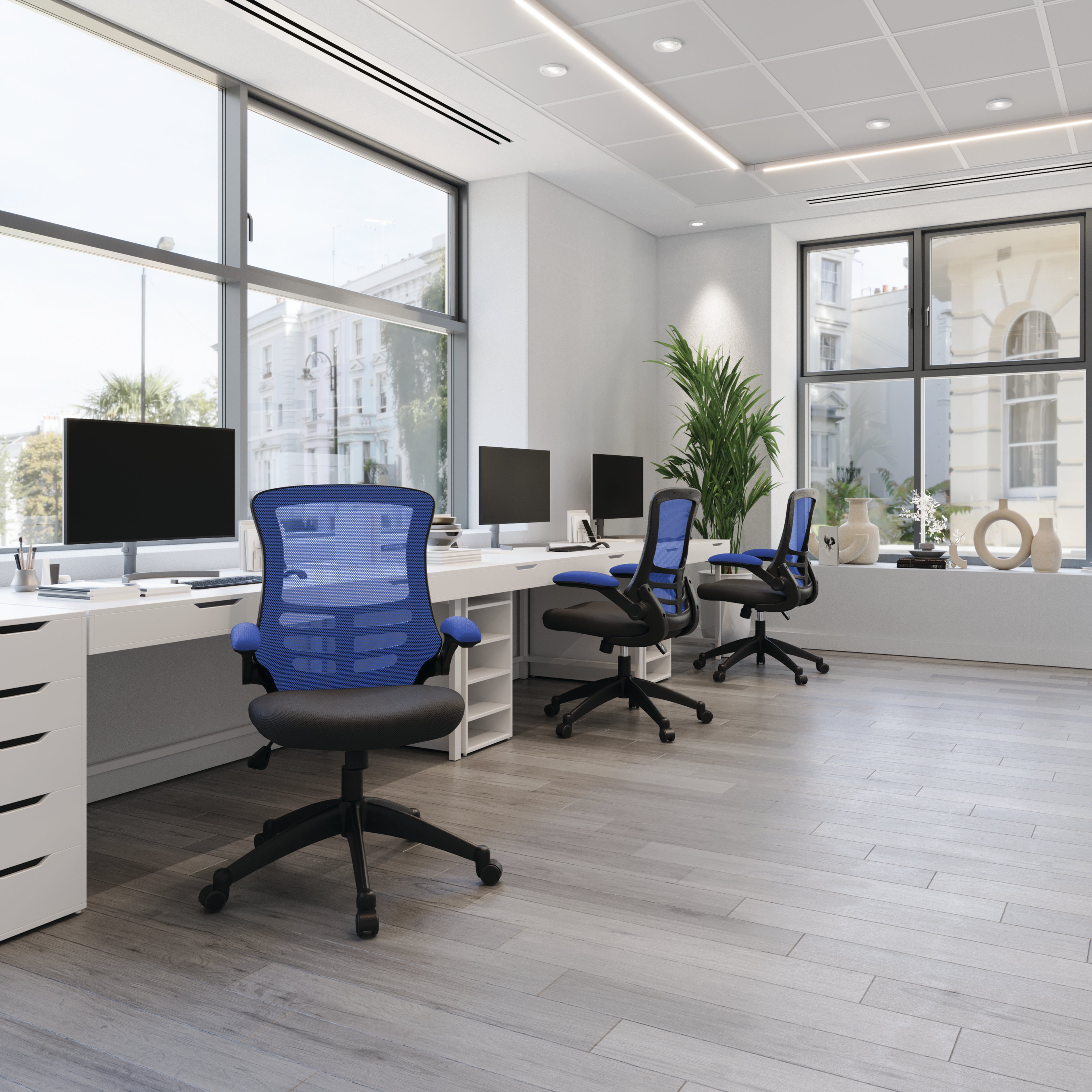 Modern office with desks, chairs, and large windows.