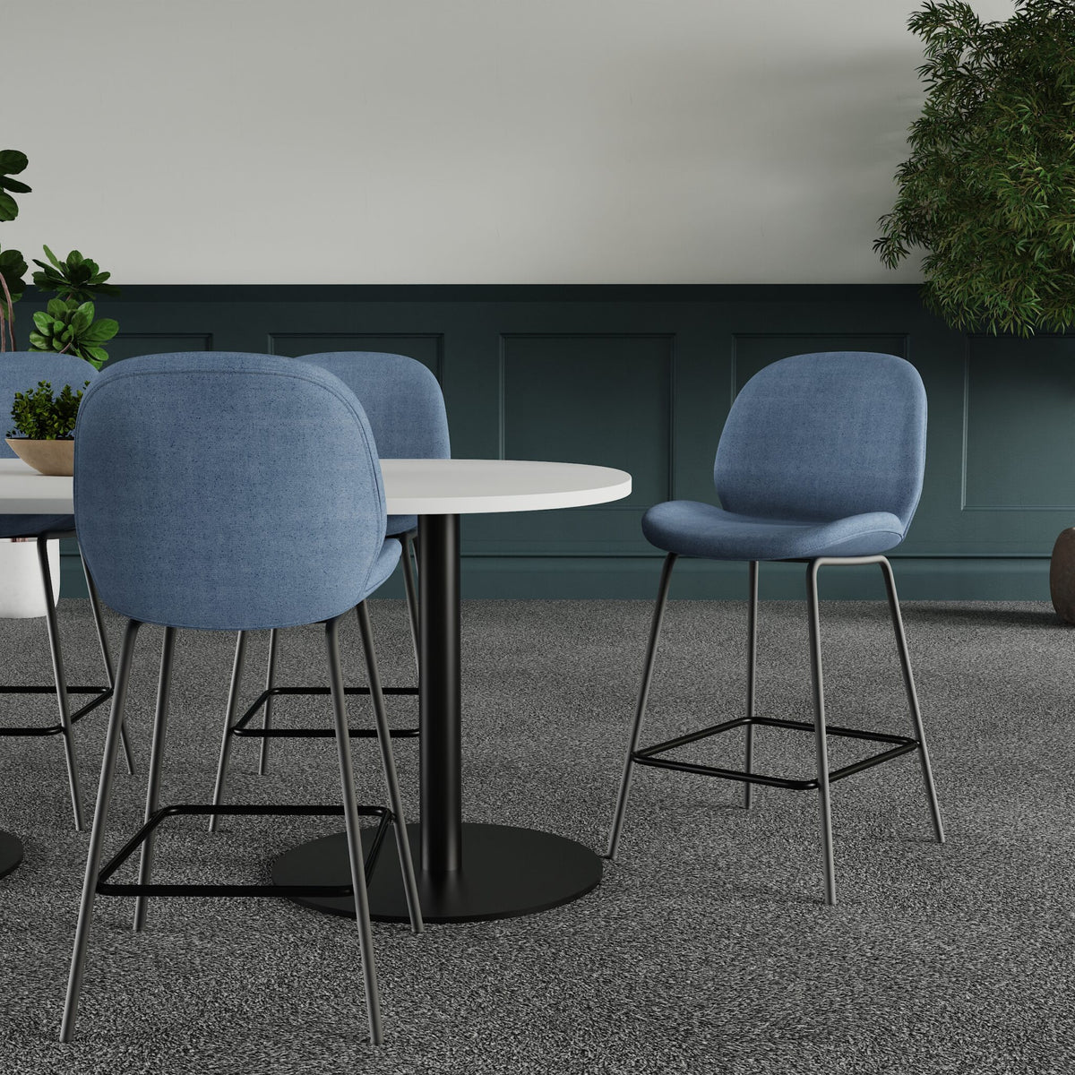 Blue chairs around a round table in a room with green paneling and plants.