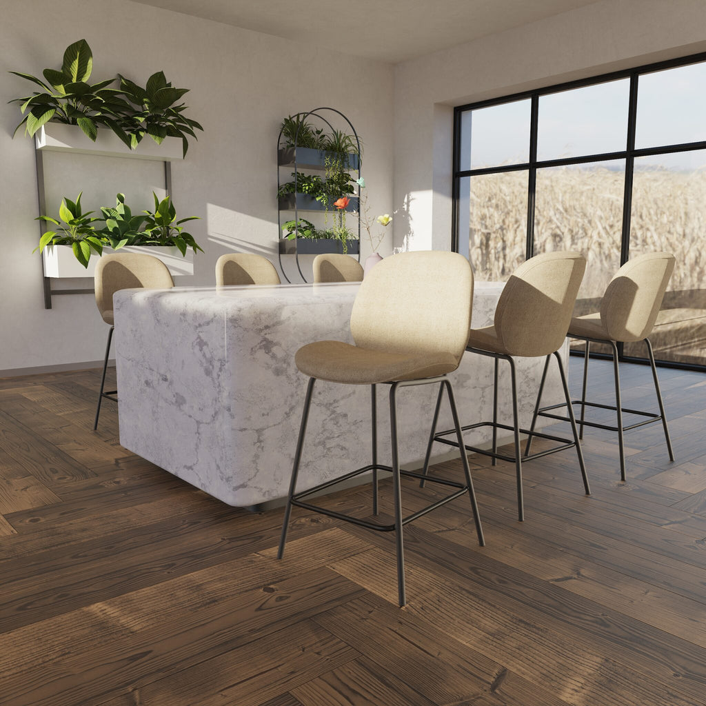 A modern kitchen island with a white marble-look surface and a row of beige bar stools with black metal legs, set in a bright room with wood flooring and large windows.