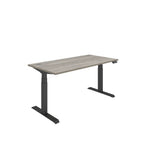 Height adjustable desk with grey wood-effect top and black frame on a white background