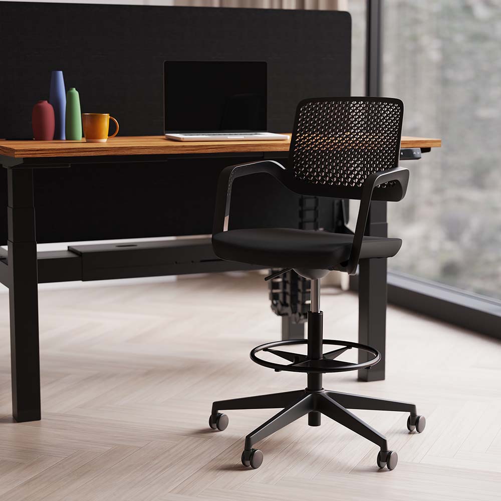 Office workstation with black high chair, desk, screen and laptop with a window in the background
