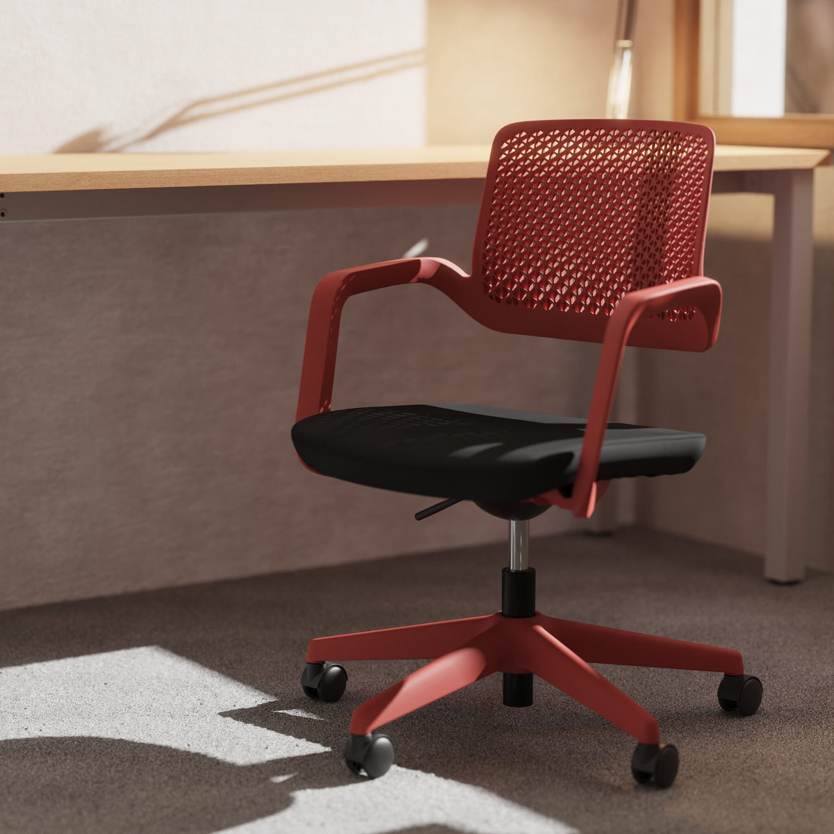 Red chair with black seat on a grey carpet with a desk in the background