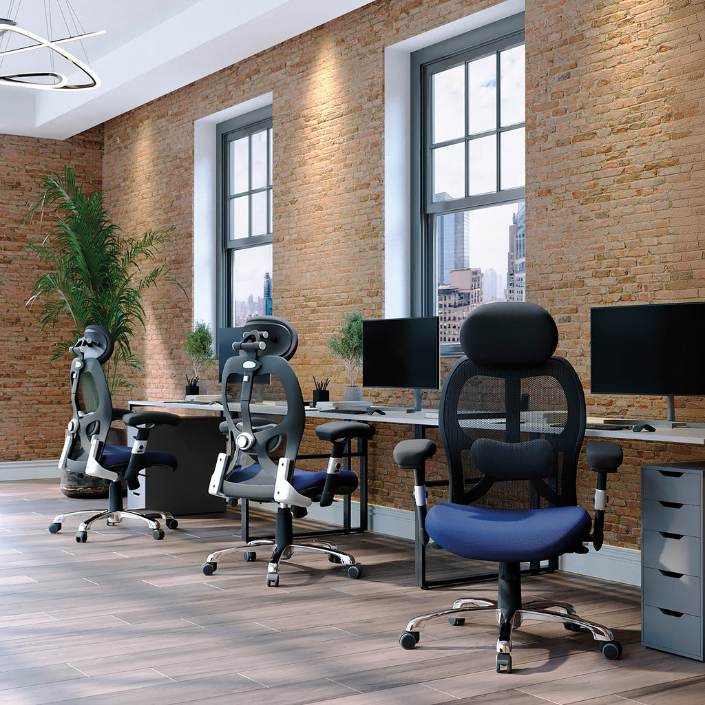 Modern office setup with ergonomic chairs and desks against a brick wall.