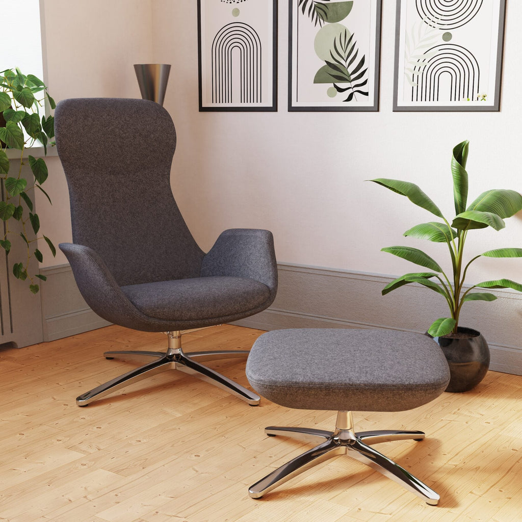 A modern grey upholstered lounge chair with a matching ottoman, both on chrome star bases, placed in a styled room with light wood flooring, framed wall art, and potted plants.