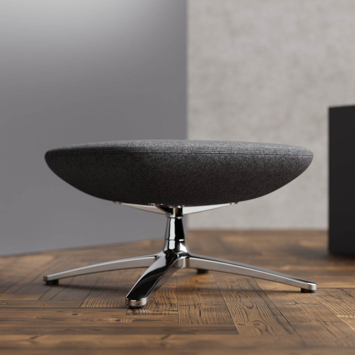 Grey footstool with a chrome frame on a wooden floor with a grey wall in a background