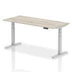 Adjustable height desk with wood-effect top and metal legs on a white background