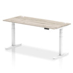 Adjustable height desk with wood-effect top and metal legs on a white background