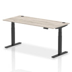 Adjustable height desk with wood-effect top and metal legs on a white background