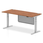 Adjustable height desk with wood-effect top and metal legs with modesty panel on a white background