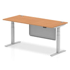 Adjustable height desk with wood-effect top and metal legs with modesty panel on a white background