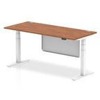 Adjustable height desk with wood-effect top and metal legs with modesty panel on a white background