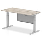 Adjustable height desk with wood-effect top and metal legs with modesty panel on a white background