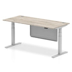 Adjustable height desk with wood-effect top and metal legs with modesty panel on a white background