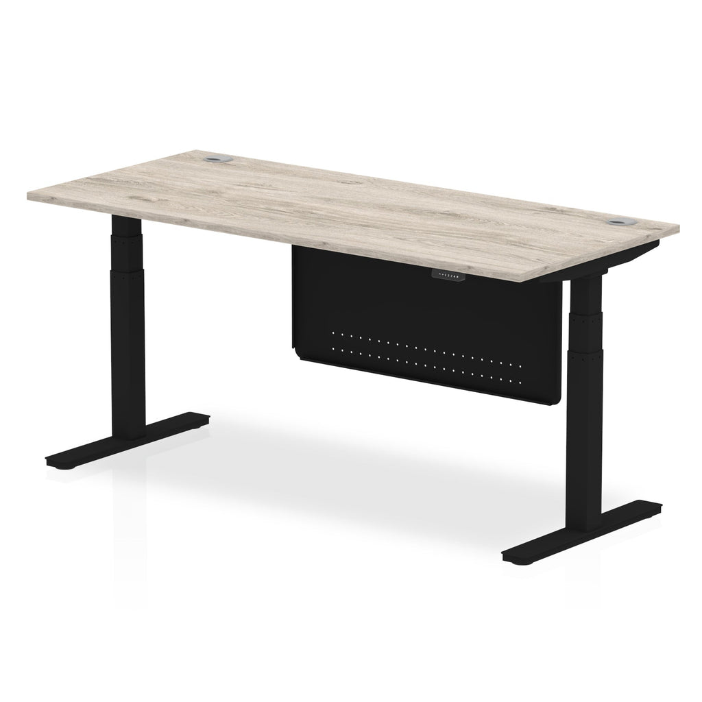 Adjustable height desk with wood-effect top and metal legs with modesty panel on a white background