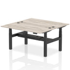 Back-to-back height adjustable desk with wood-effect top and metal frame on a white background