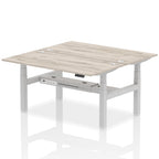 Back-to-back height adjustable desk with wood-effect top and metal frame on a white background
