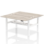 Back-to-back height adjustable desk with wood-effect top and metal frame on a white background