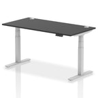 Adjustable height desk with black top and metal legs on a white background