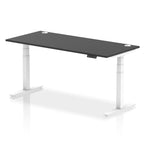 Adjustable height desk with black top and metal legs on a white background