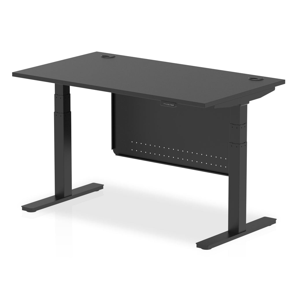 Adjustable height desk with black top and metal legs with modesty panel on a white background