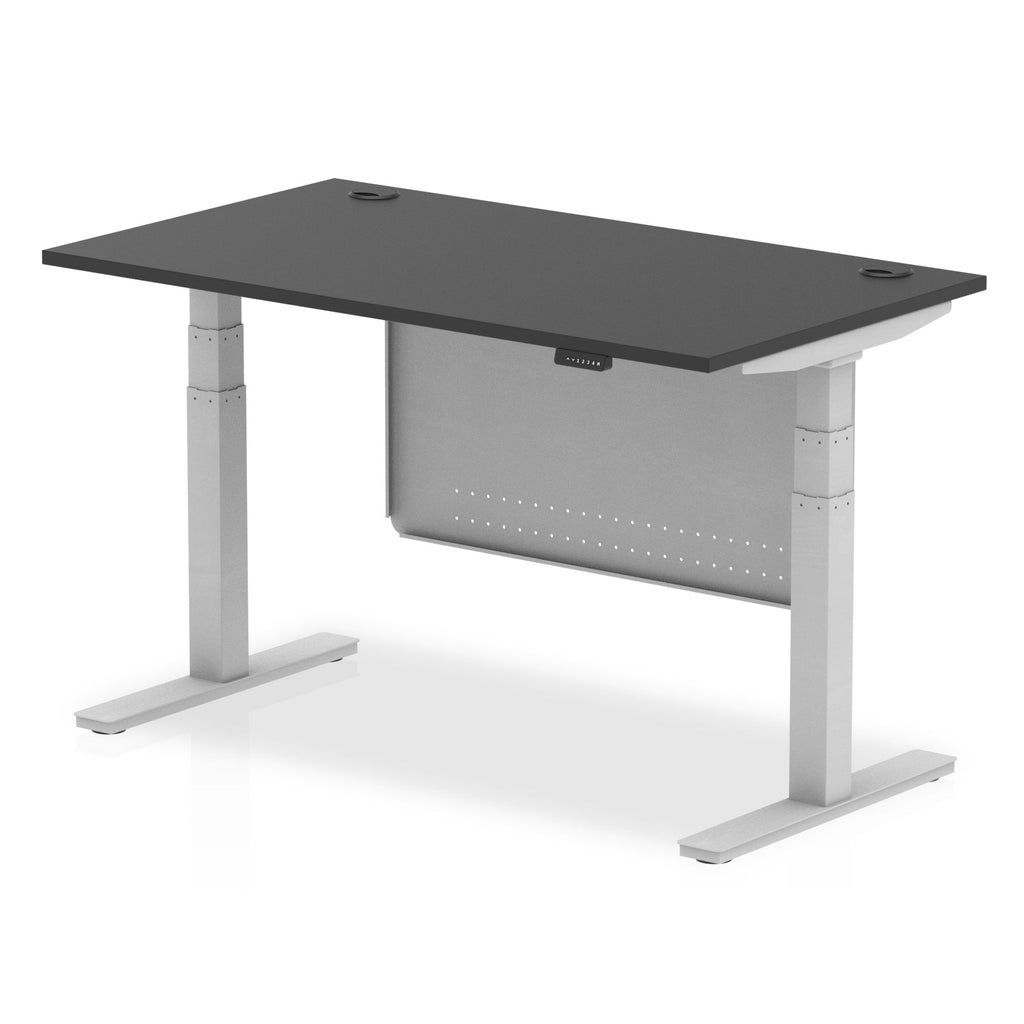 Adjustable height desk with black top and metal legs with modesty panel on a white background