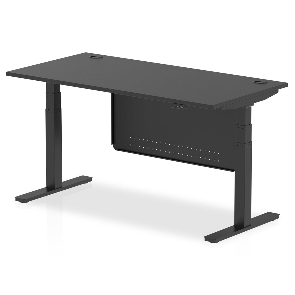 Adjustable height desk with black top and metal legs with modesty panel on a white background