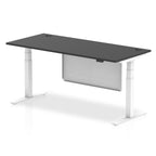Adjustable height desk with black top and metal legs with modesty panel on a white background