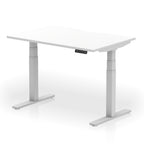 Height adjustable desk with white top and silver frame on a white background